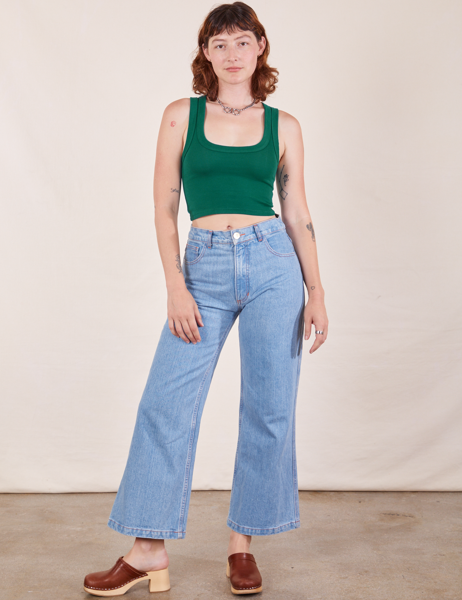 Alex is wearing Cropped Tank Top in Hunter Green and light wash Sailor Jeans