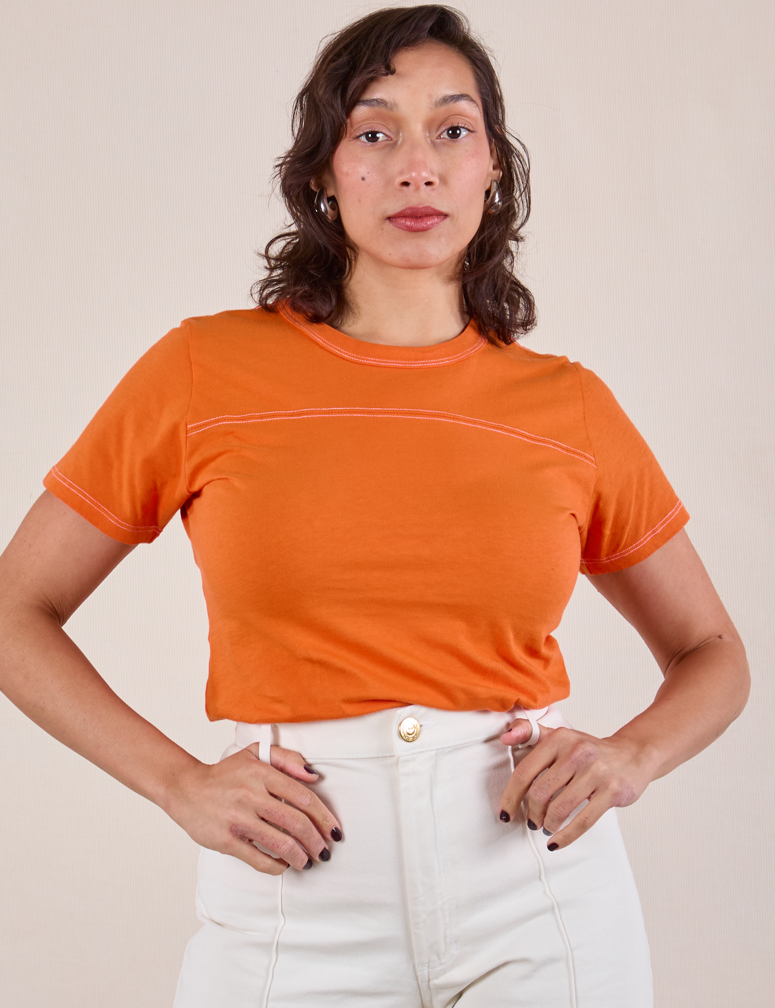 Tiara is wearing JV Tee in Construction Orange tucked into vintage tee off-white Western Pants