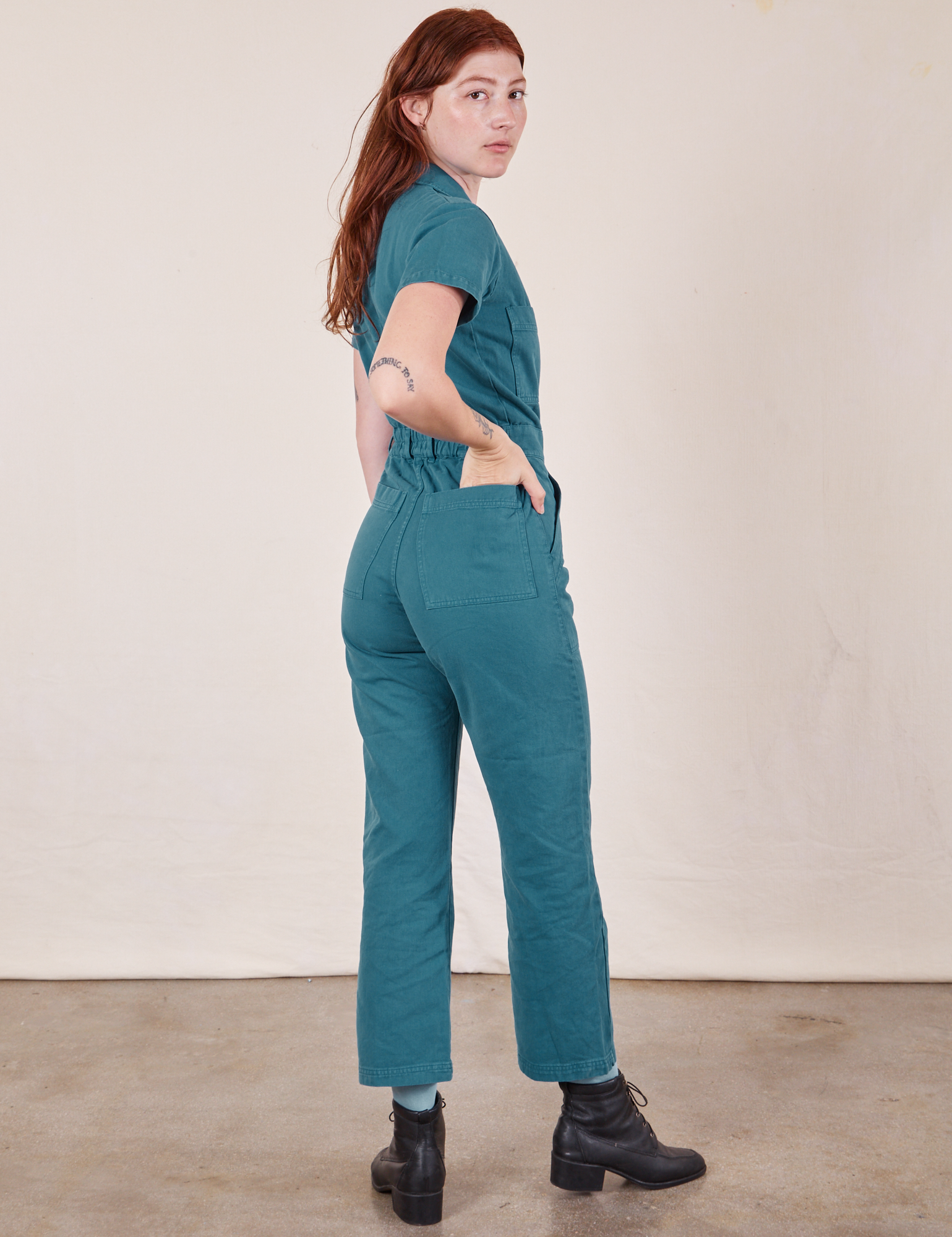 Angled back view of Short Sleeve Jumpsuit in Marine Blue worn by Alex