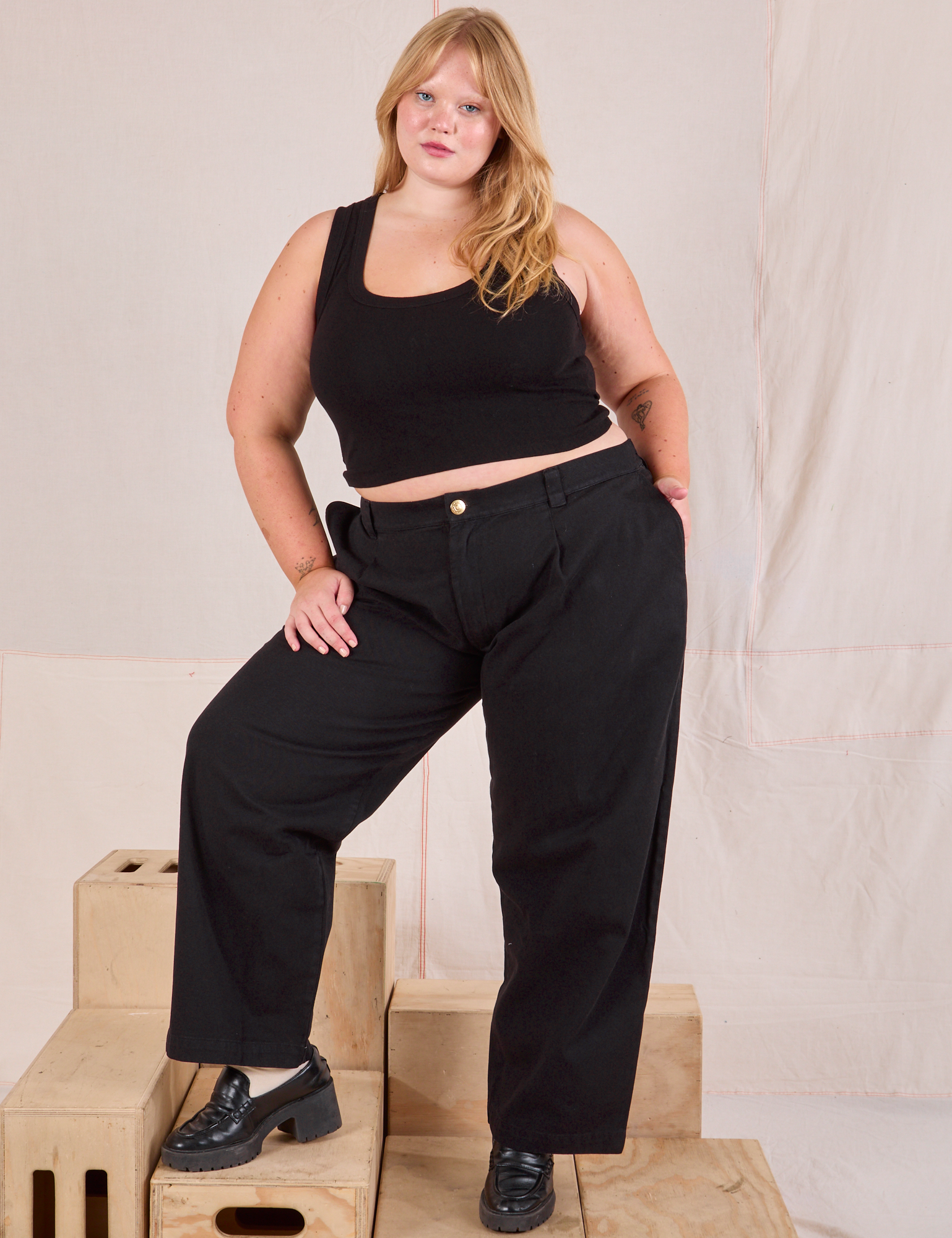 Juliet is 5&#39;7&quot; and wearing 0XL Mid-Rise Pleated Trousers in Basic Black paired with black Cropped Tank