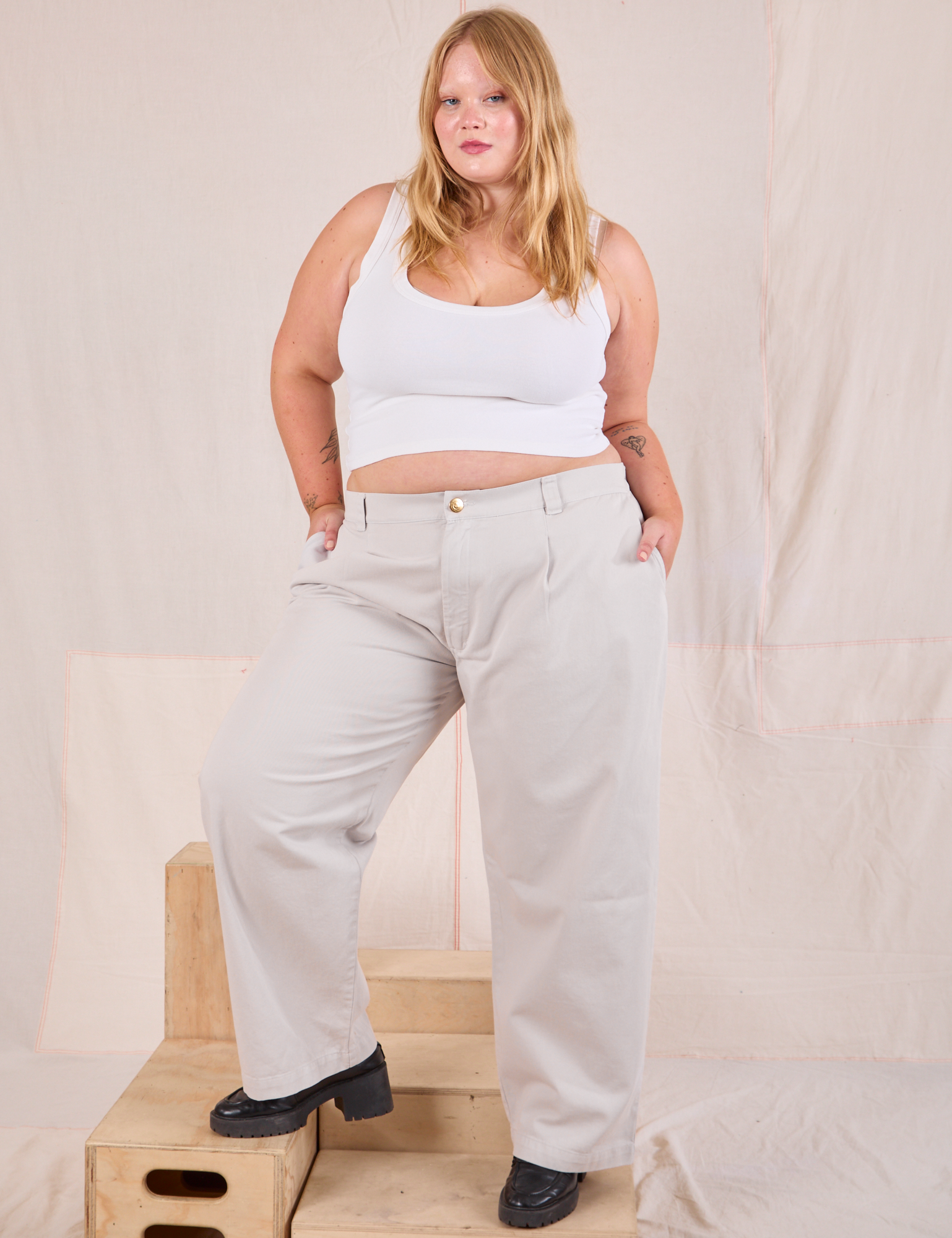 Juliet is 5&#39;7&quot; and wearing 0XL Mid-Rise Pleated Trousers in Stone White paired with a Cropped Tank in Vintage Tee Off-White