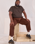 Elijah is wearing Mid-Rise Work Pants in Fudgesicle Brown and espresso brown Organic Vintage Tee