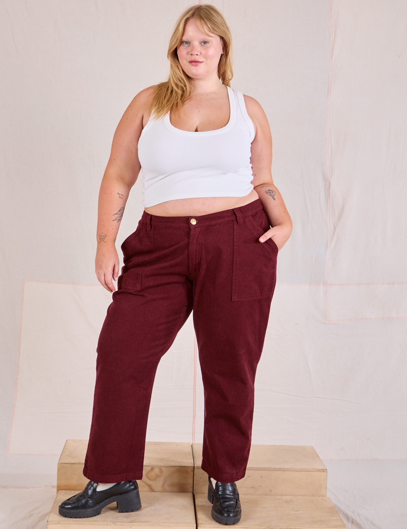 Juliet is 5&#39;7&quot; and wearing 2XL Mid-Rise Work Pants in Red Wine paired with a Cropped Tank in vintage tee off-white