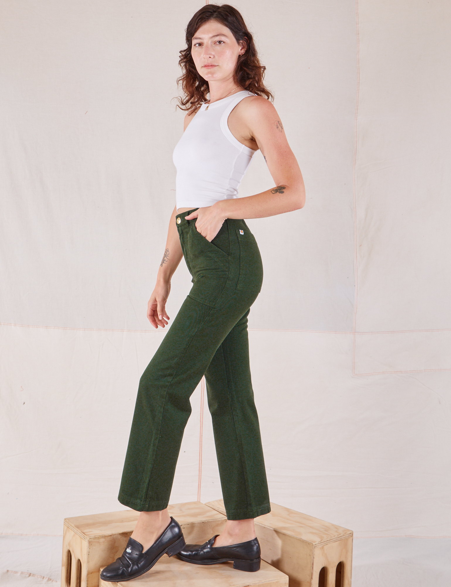 Side view of Organic Work Pants in Swamp Green and Racerback Tank in vintage tee off-white on Alex