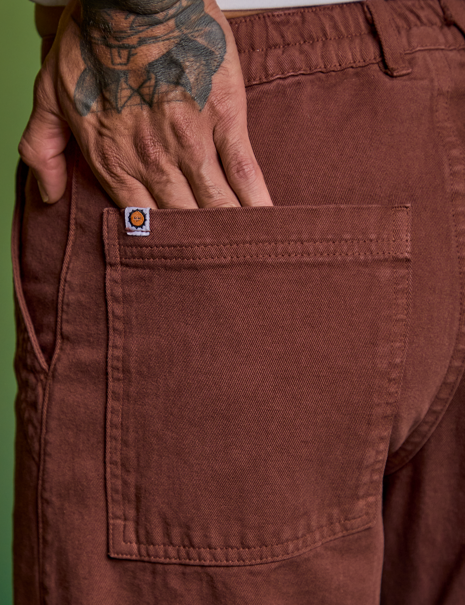 Close up of Jesse&#39;s hand in the back pocket of Paintstamped Work Pants in Mushroom