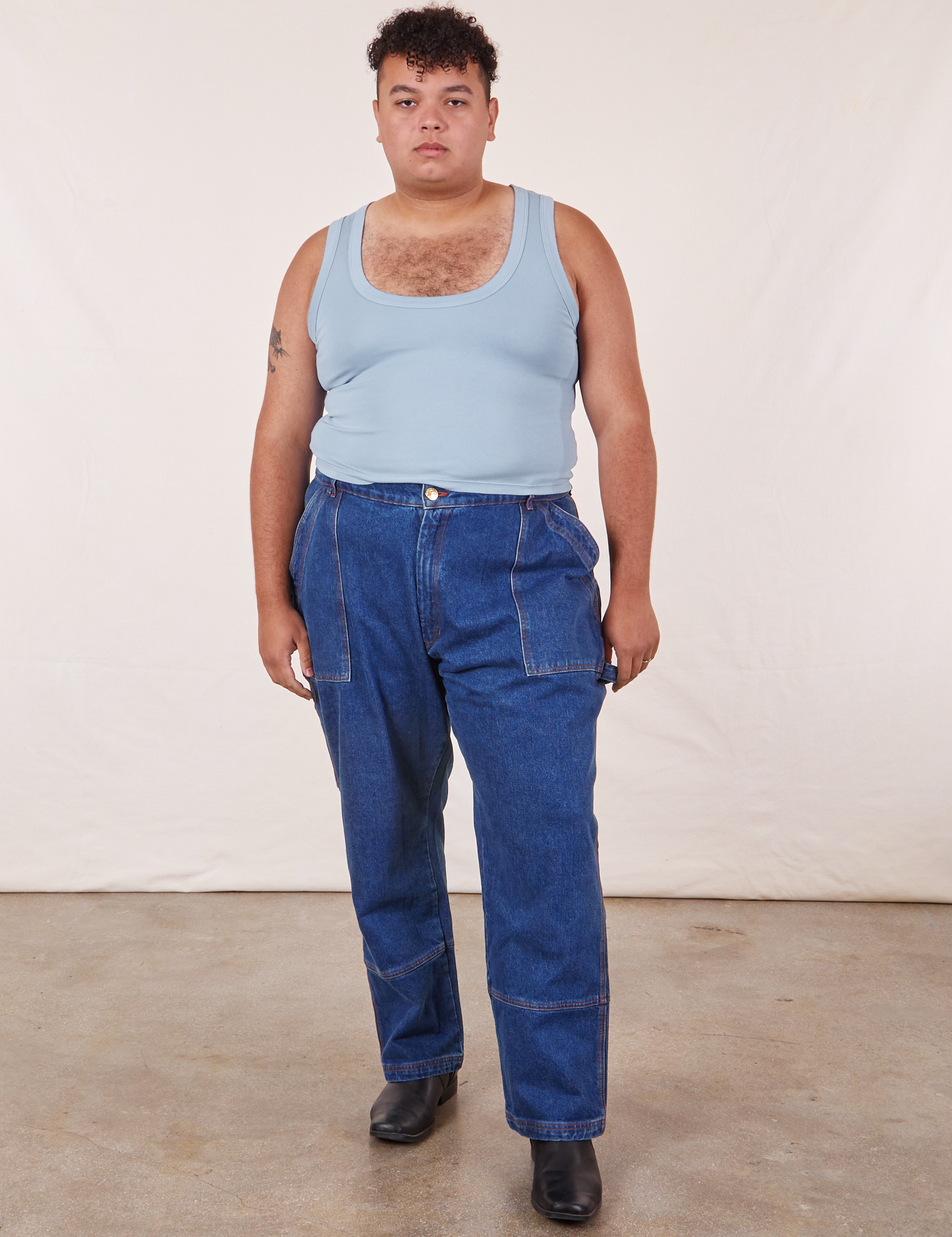 Miguel is 6&#39;0&quot; and wearing 1XL Cropped Tank Top in Periwinkle paired with dark wash Carpenter Jeans