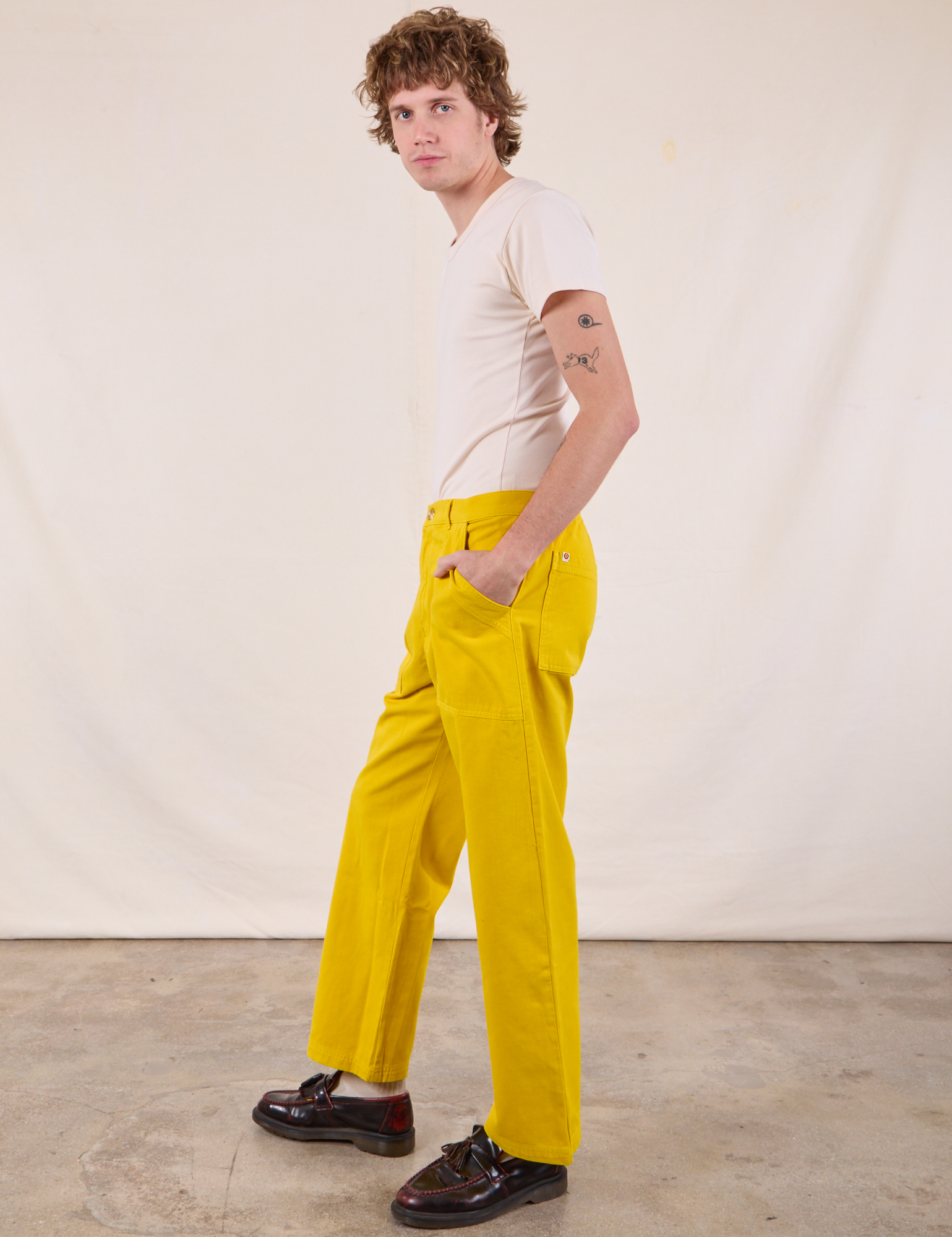 Side view of Work Pants in Golden Yellow and Burly Tee in Vintage Tee Off-White on Quinn