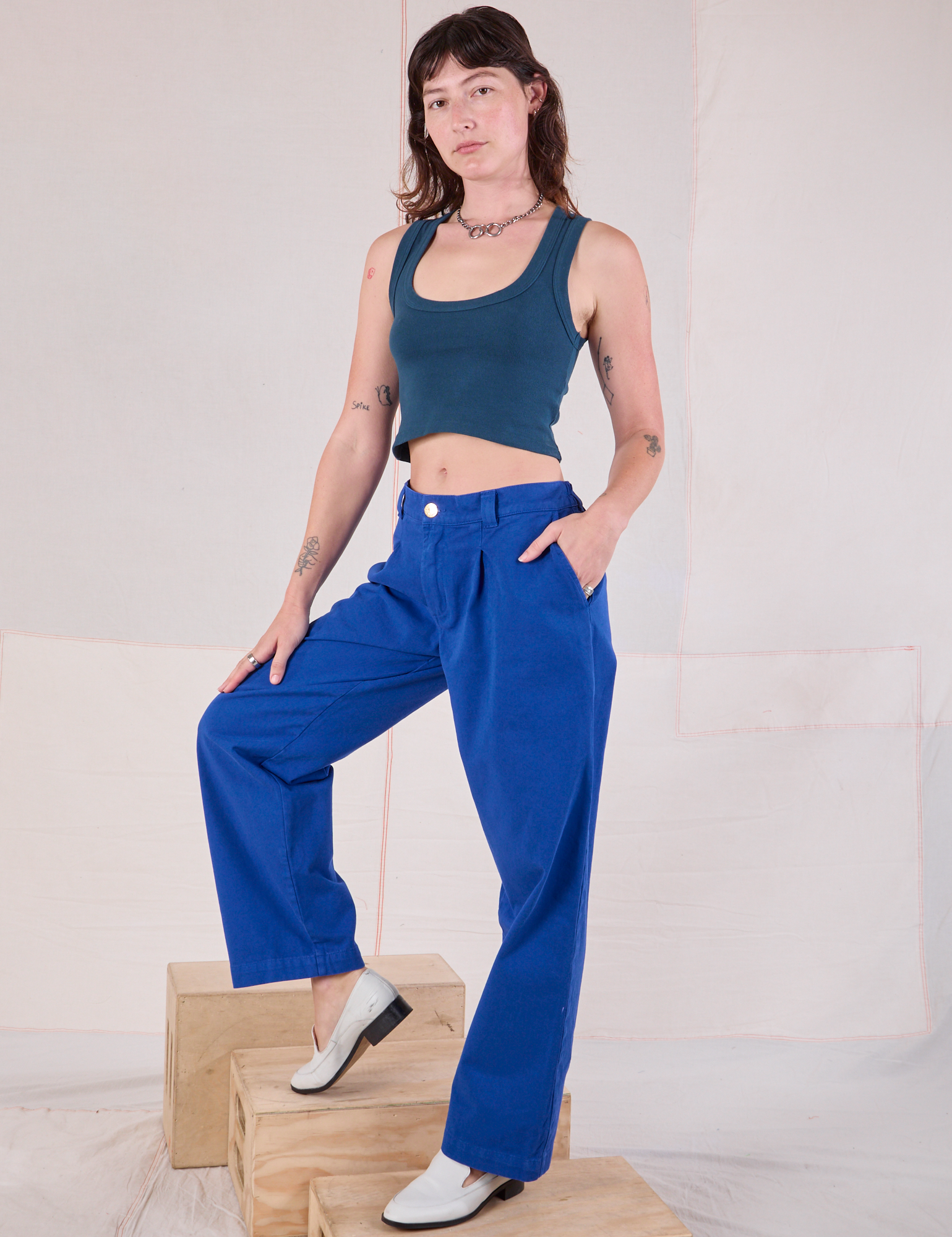 Angled front view of Mid-Rise Pleated Trousers in Royal Blue and lagoon Cropped Tank on Alex