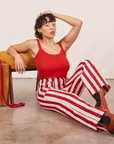 Tiara is wearing Work Pants in Cherry Stripe and mustang red Cropped Cami. She is sitting on the floor.