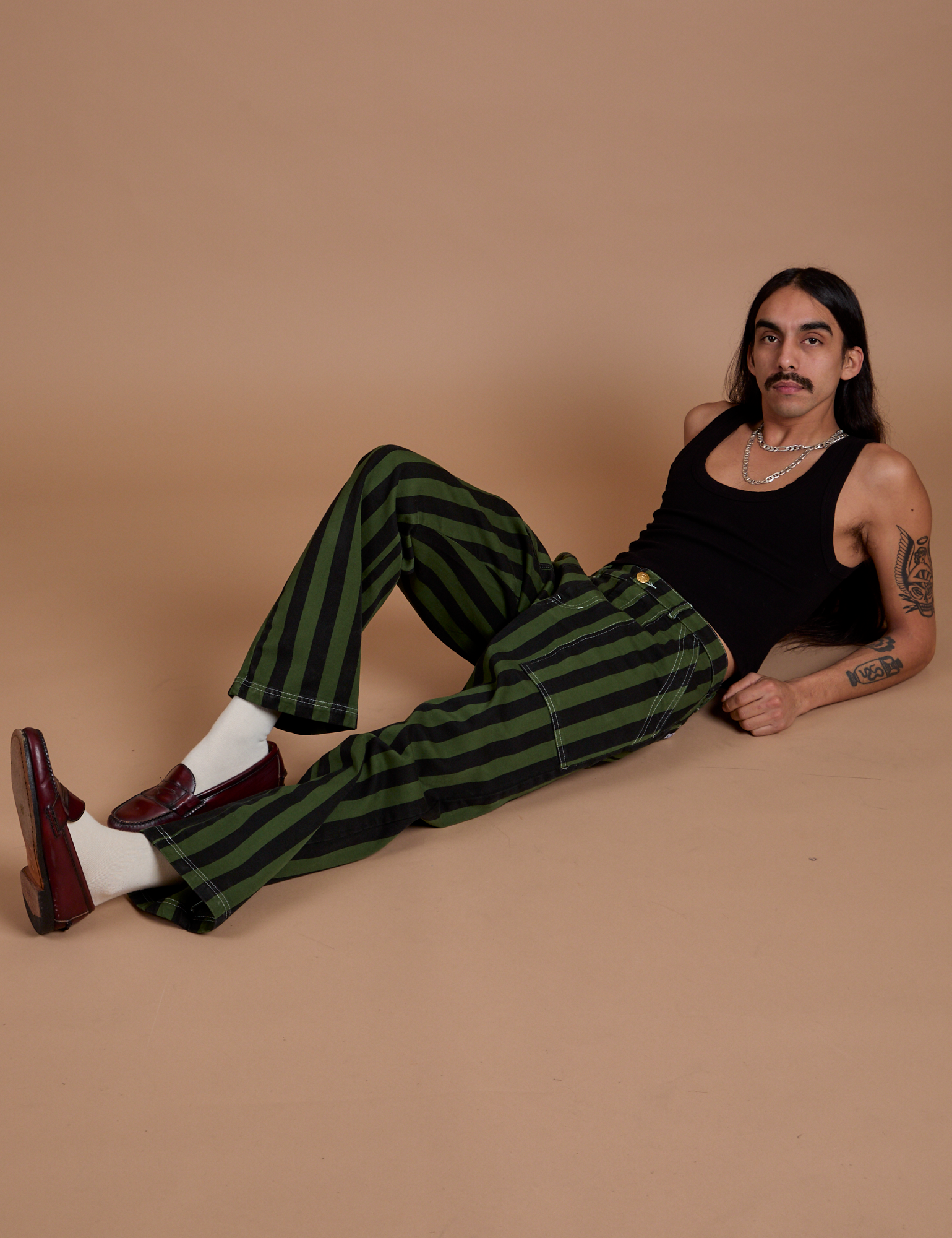 Anthony is wearing Black Stripe Work Pants in Evergreen and black Cropped Tank