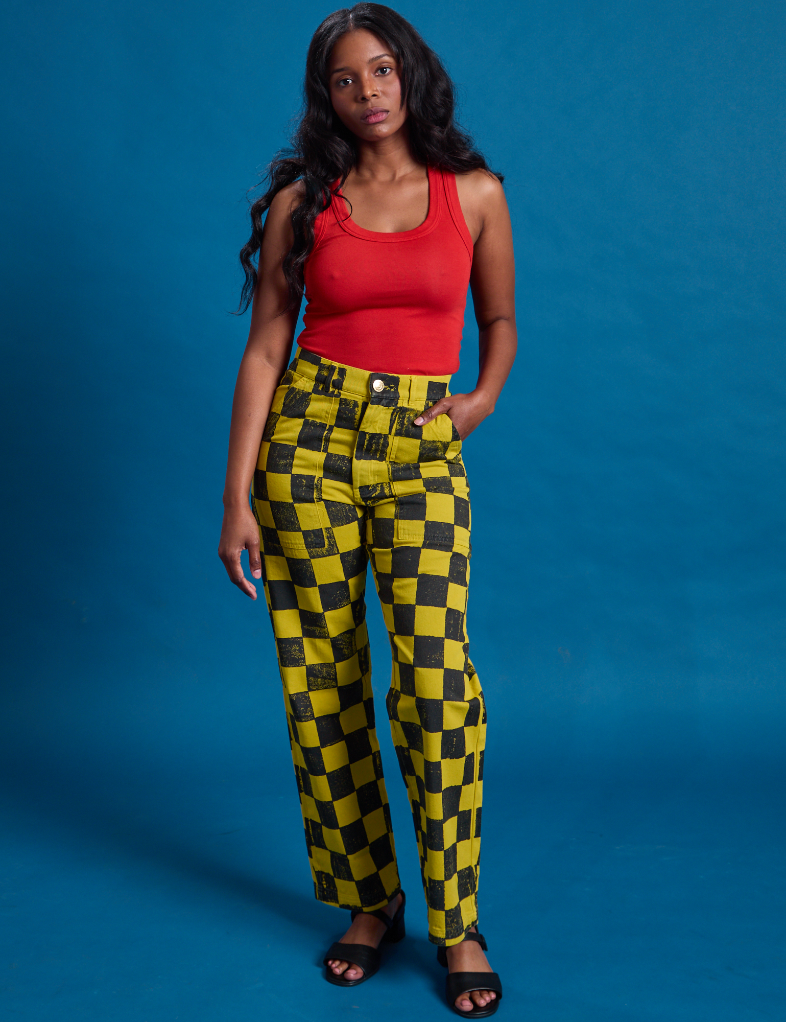 Kandia is 5&#39;3&quot; and wearing XS Checkerboard Work Pants in Yellow/Black paired with mustang red Tank Top