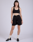 Alex is 5’8” and wearing XXS Pleated Trouser Shorts in Basic Black paired with black Mini Tank