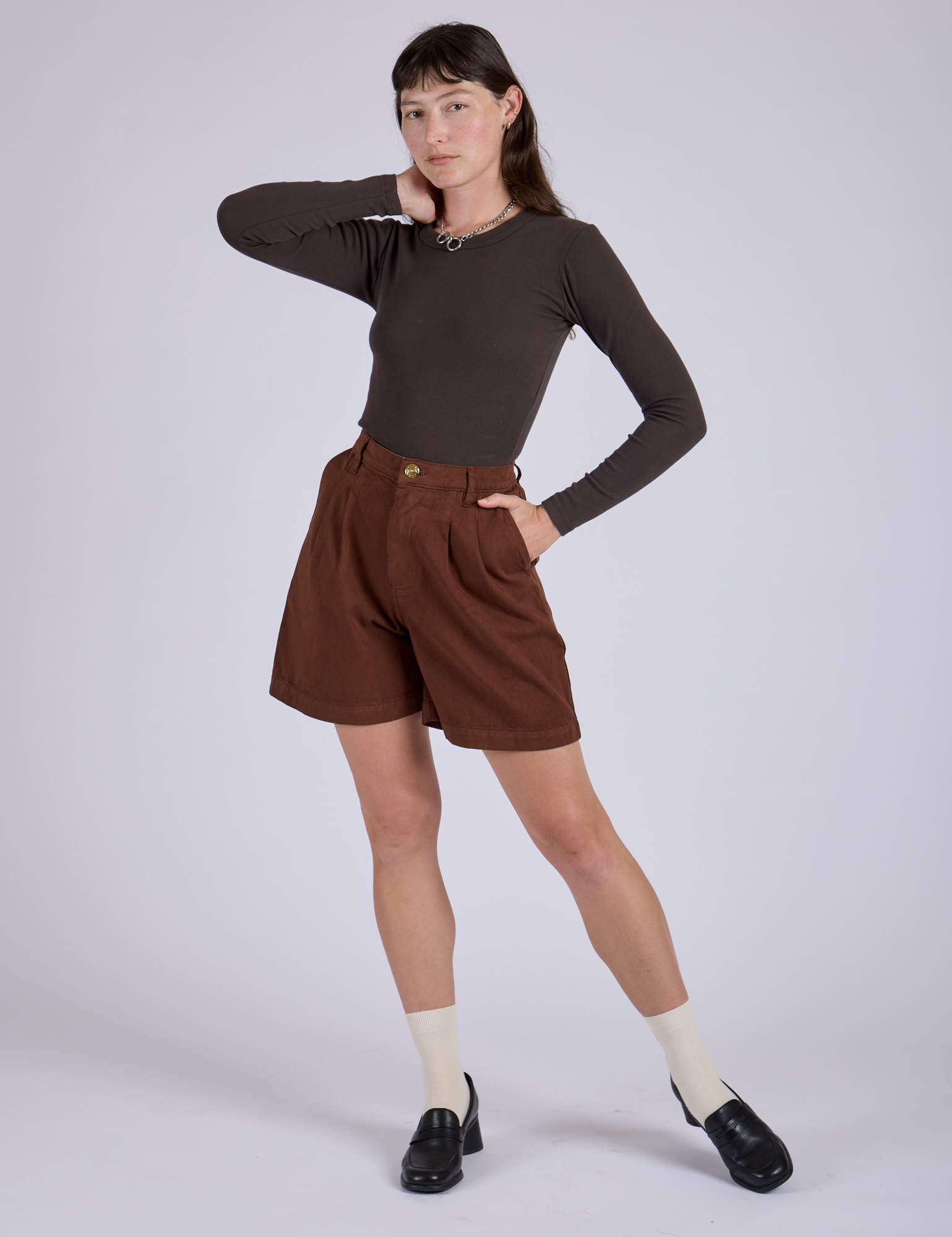 Alex is 5’8” and wearing XXS Pleated Trouser Shorts in Fudgesicle Brown paired with espresso brown Long Sleeve Baby Tee