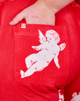 Close up of Juliet's hand in the back pocket of Airbrush Cupid Work Pants. 