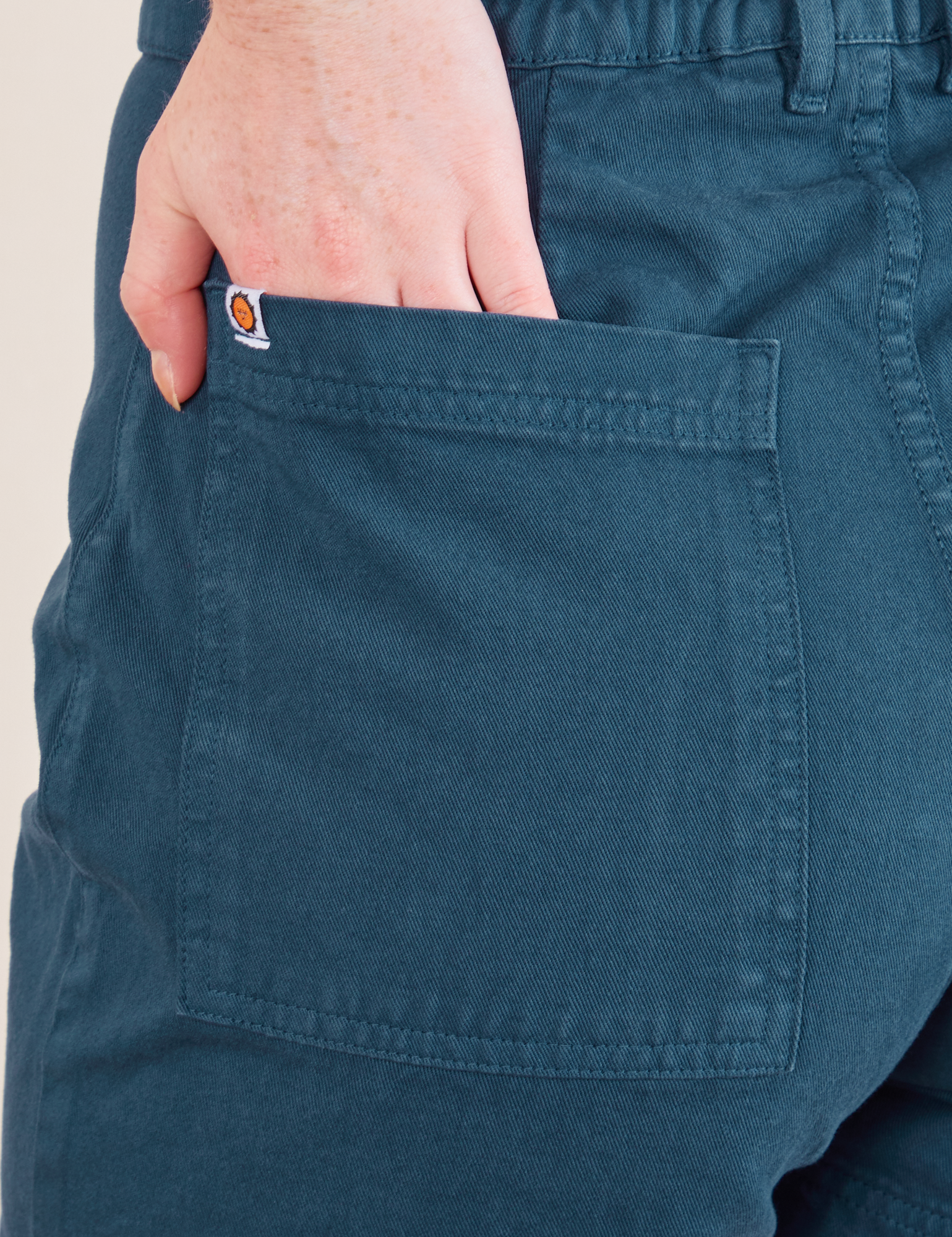 Western Shorts in Lagoon back pocket close up. Margaret has their hands in the pocket.