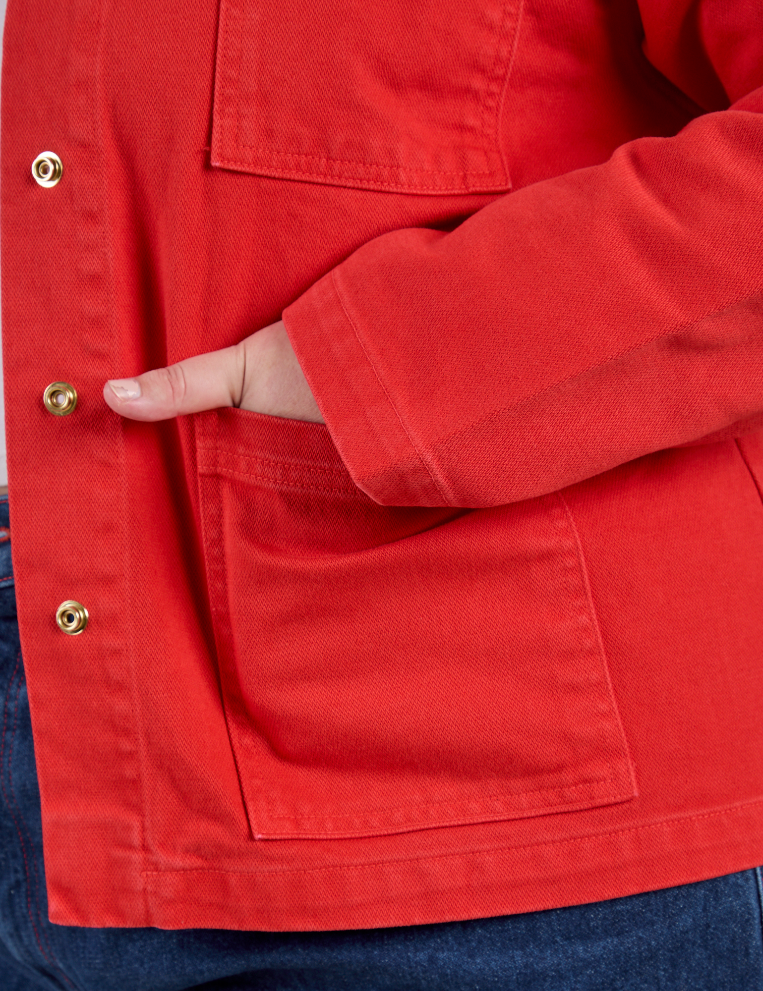Close up of Juliet&#39;s hand in the front pocket of Denim Work Jacket in Mustang Red