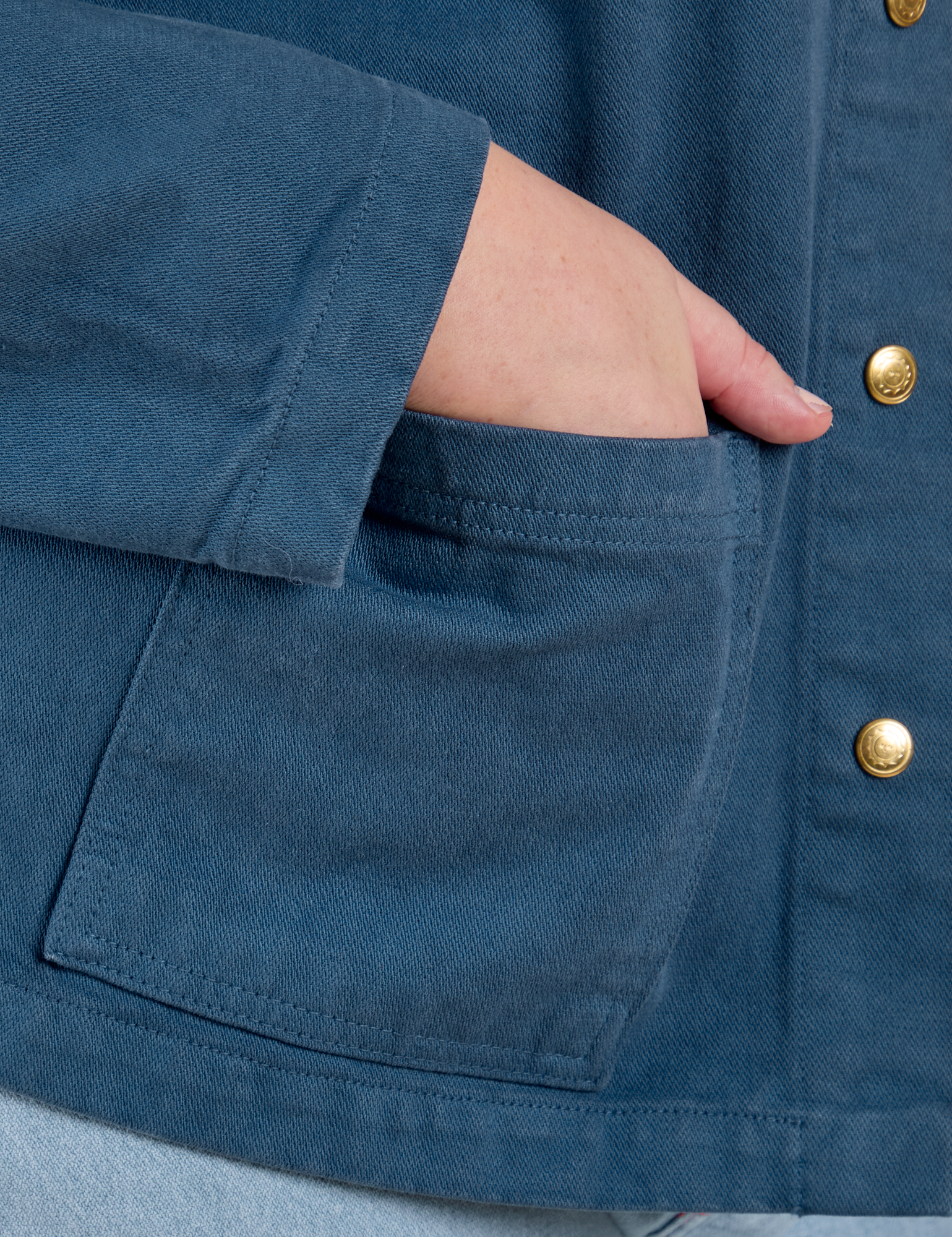 Close up of Juliet&#39;s hand in the front pocket of Denim Work Jacket in French Blue