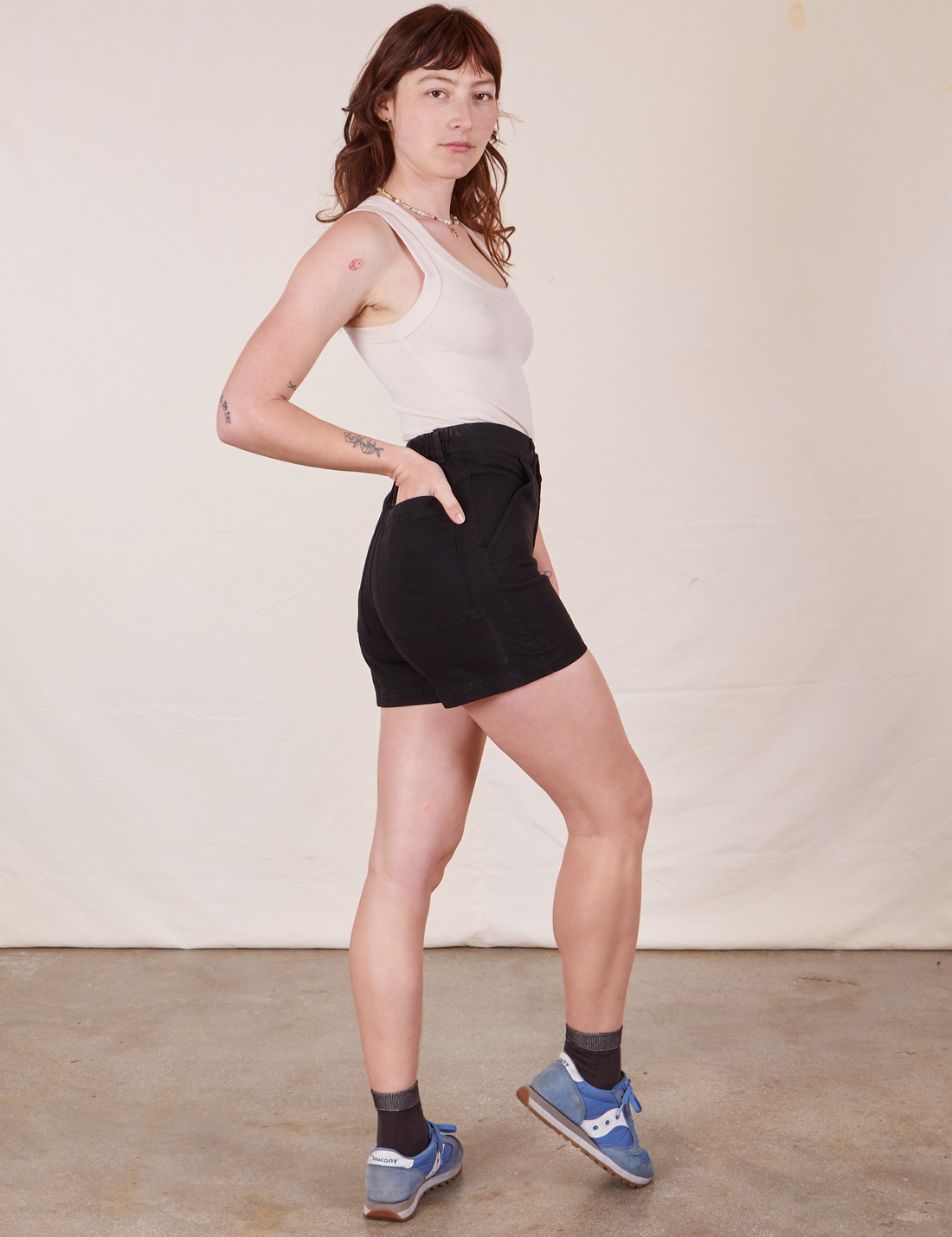 Side view of Classic Work Shorts in Basic Black and vintage off-white Tank Top worn by Alex