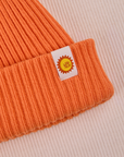 Ribbed Beanie in Construction Orange close up of sun baby tag.