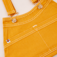 Overall Handbag in Mustard Yellow. Contrast white stitching. Brass sun baby buttons and hardware.