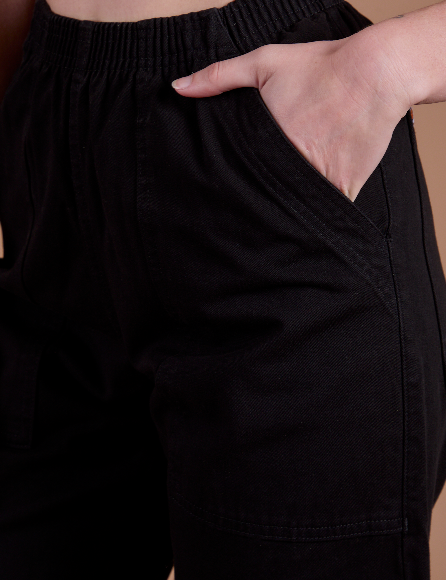 Close up of Alex's hand in the front pocket of Action Pants in Basic Black