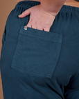 Close up of Juliet's hand in the back pocket of Action Pants in Lagoon