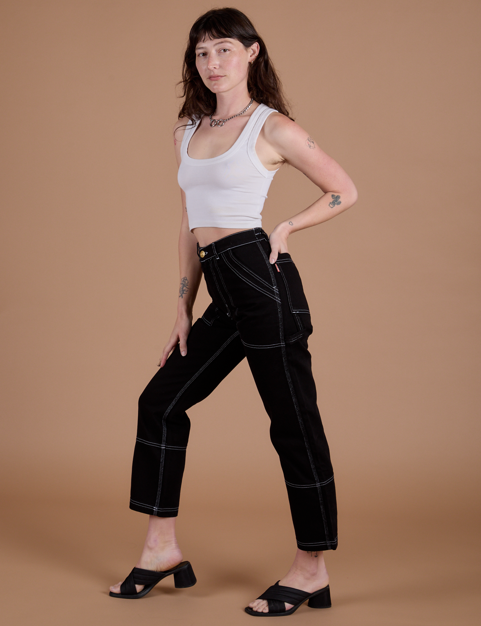 Side view of Carpenter Jeans in Black and Cropped Tank in Vintage Tee White on Alex