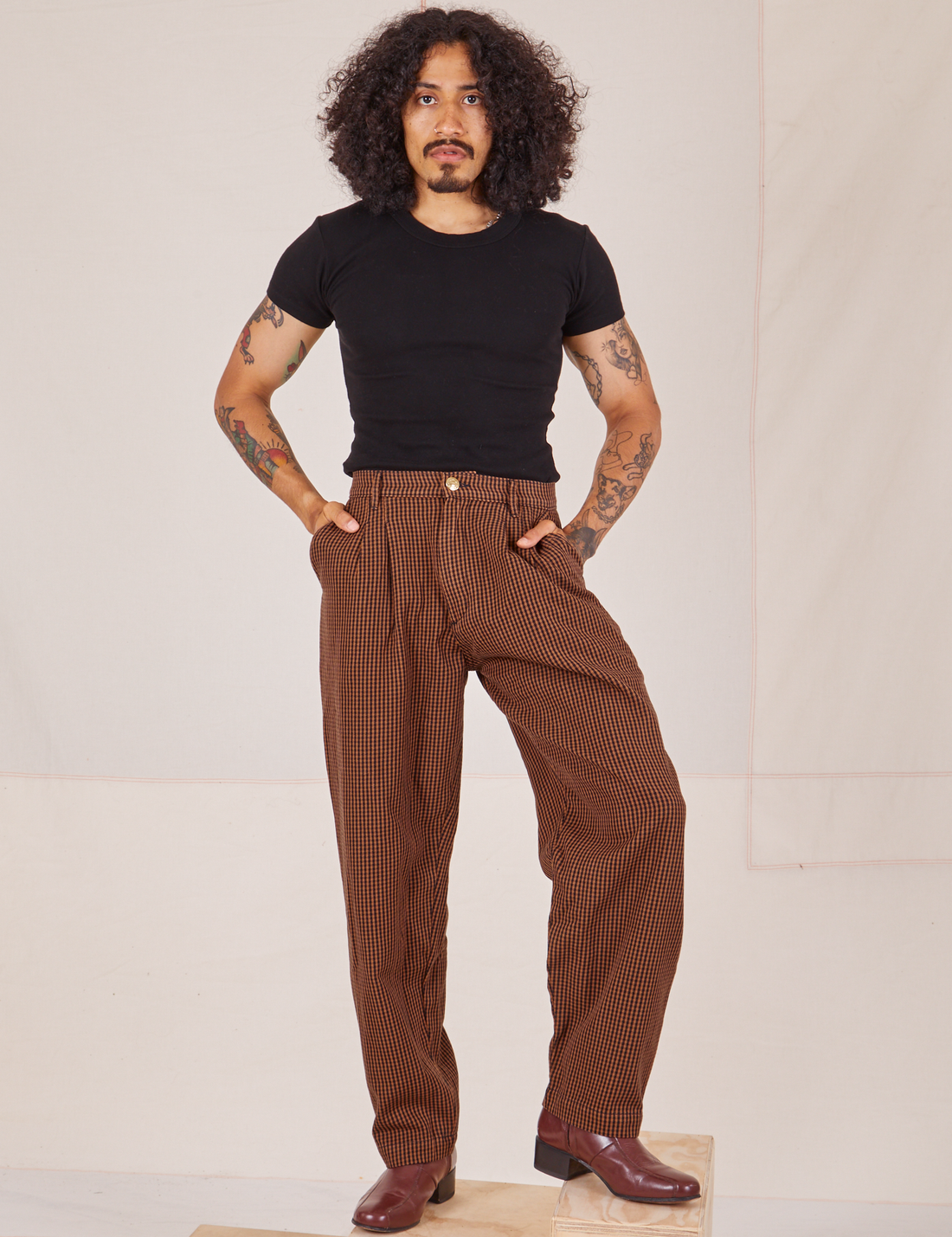 Jesse is 5'8" and wearing XS Checker Trousers in Brown paired with black Baby Tee