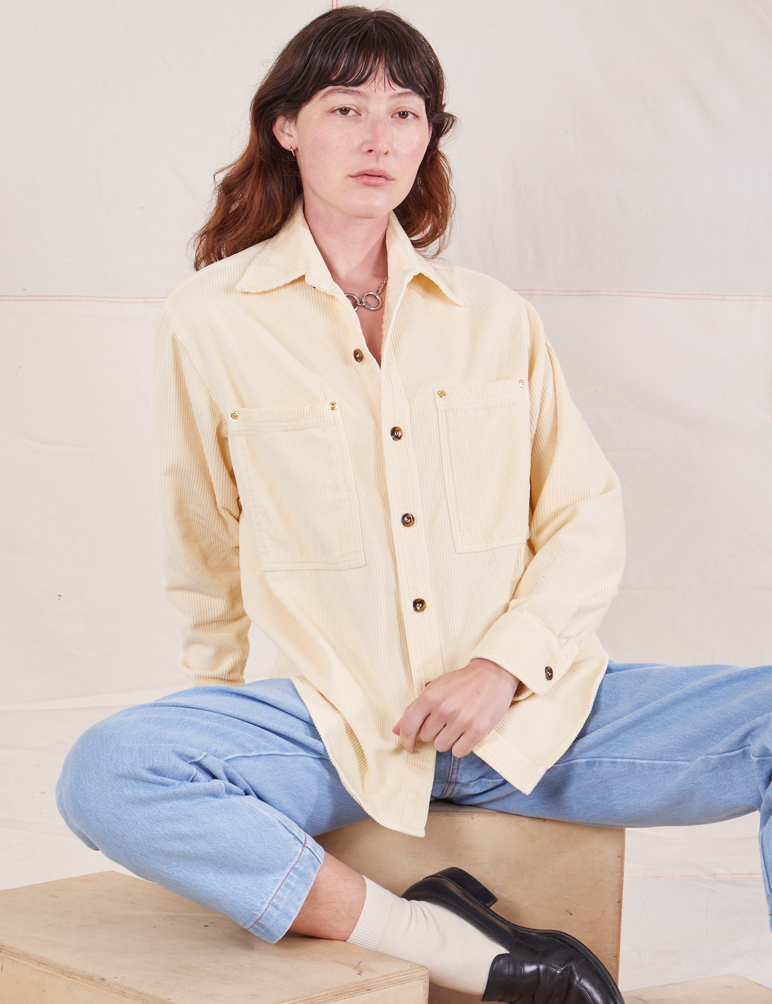 Alex is wearing a buttoned up Corduroy Overshirt in Vintage Off-White and light wash Denim Trouser Jeans