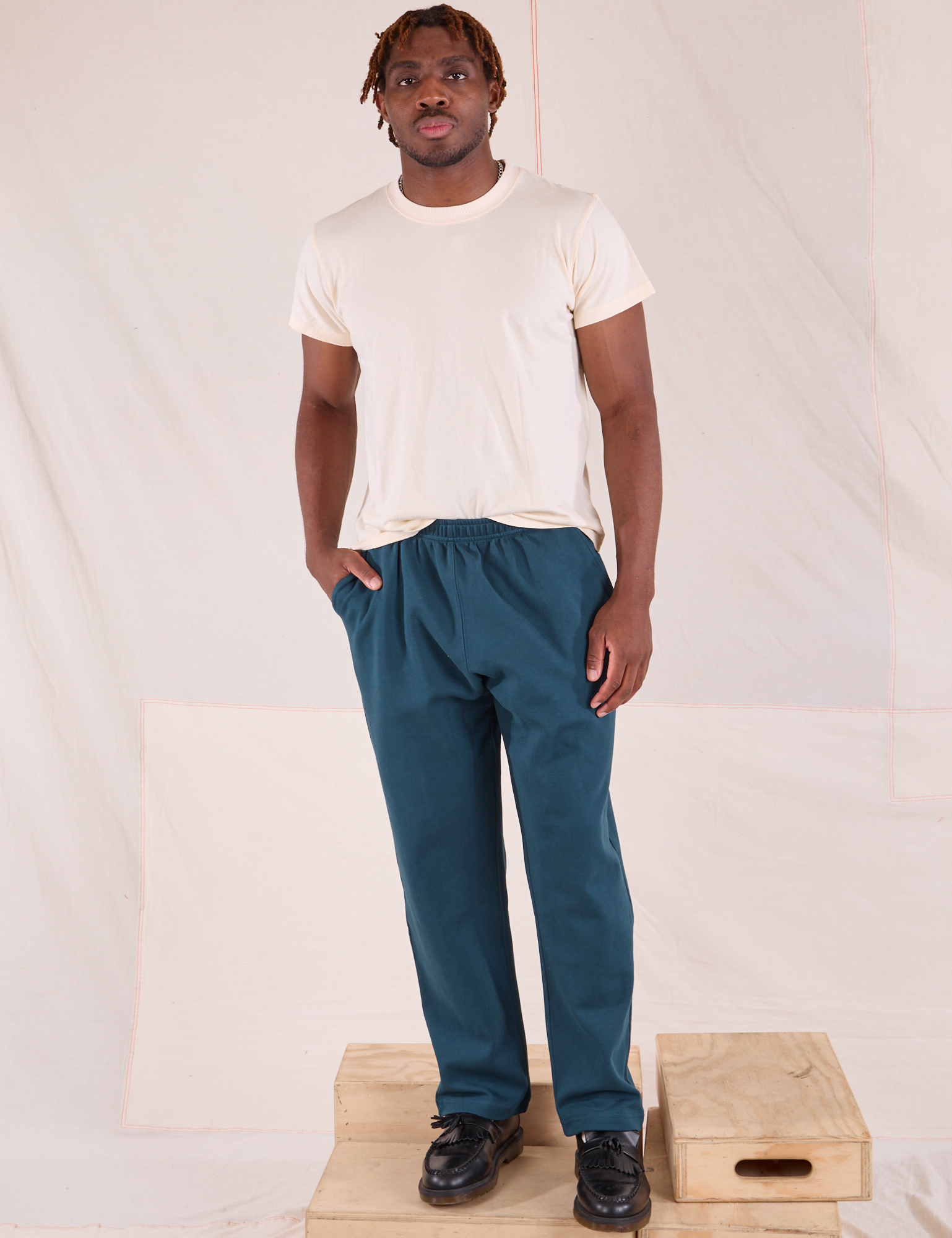 Issac is wearing Easy Pants in Lagoon and Organic Vintage Tee in vintage tee off-white