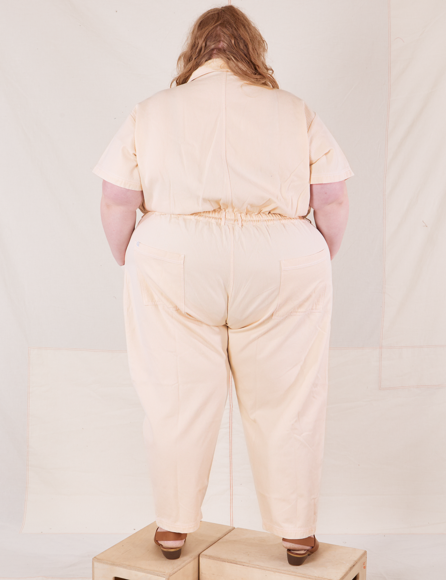 Back view of Heritage Short Sleeve Jumpsuit in Natural worn by Catie