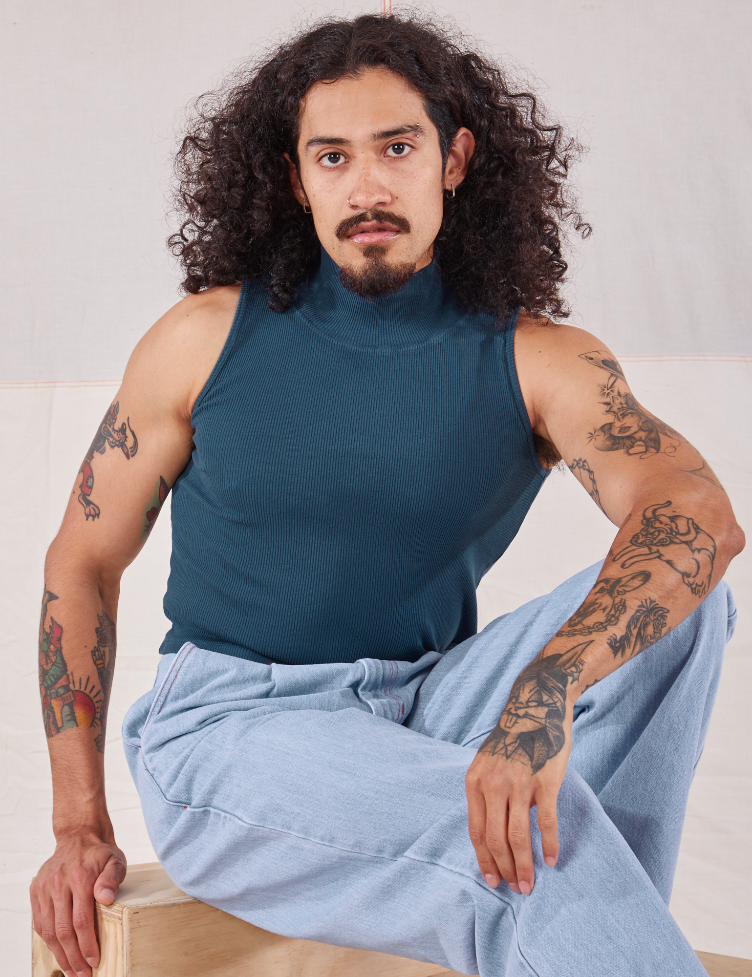 Jesse is wearing Sleeveless Essential Turtleneck in Lagoon and light wash Trouser Jeans