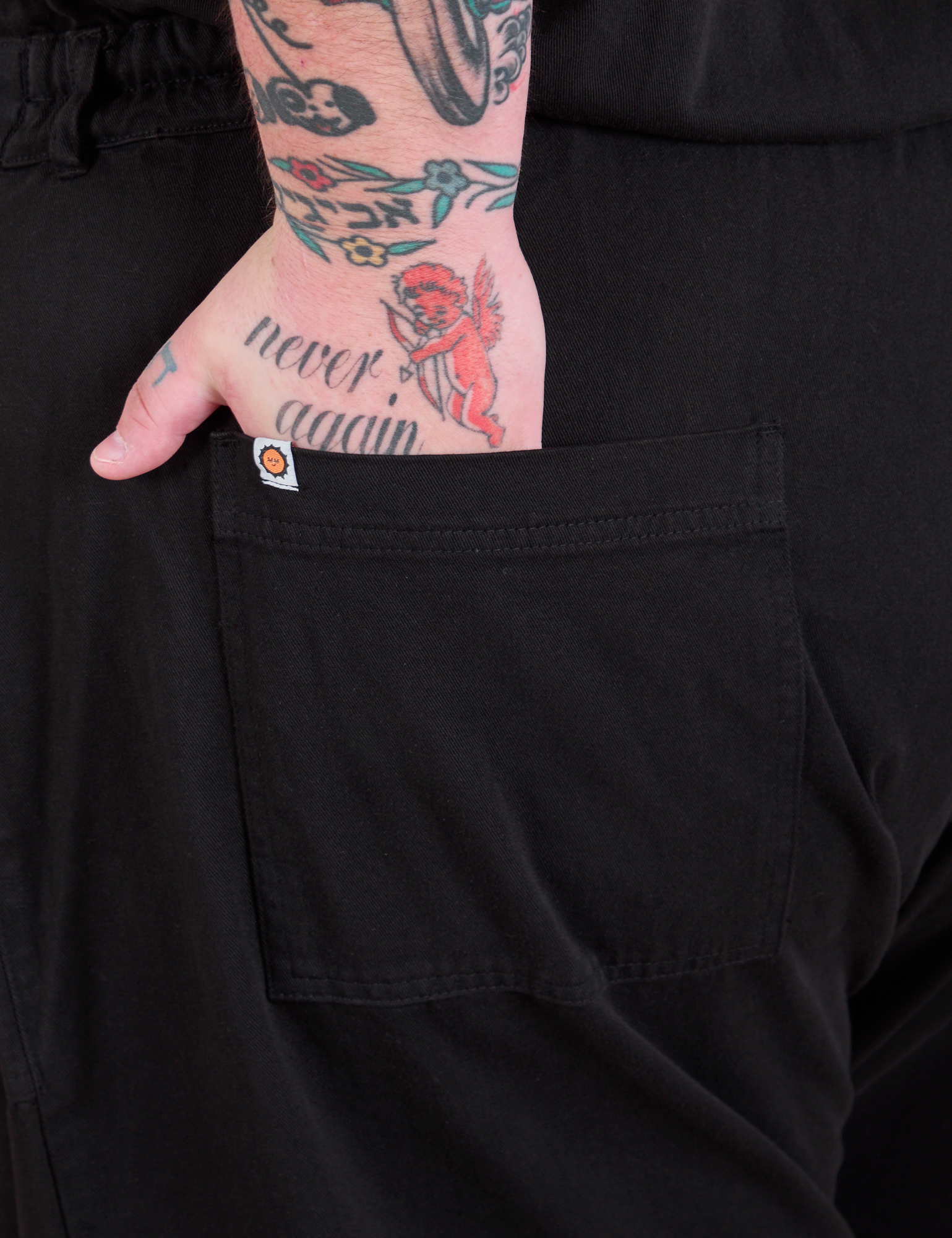 Close up of Sam&#39;s hand in the back pocket of a Long Jumpsuit in Basic Black