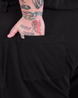 Close up of Sam's hand in the back pocket of a Long Jumpsuit in Basic Black