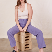 Allison is sitting on a stack of wooden crates wearing Work Pants in Faded Grape and a vintage off-white Tank Top
