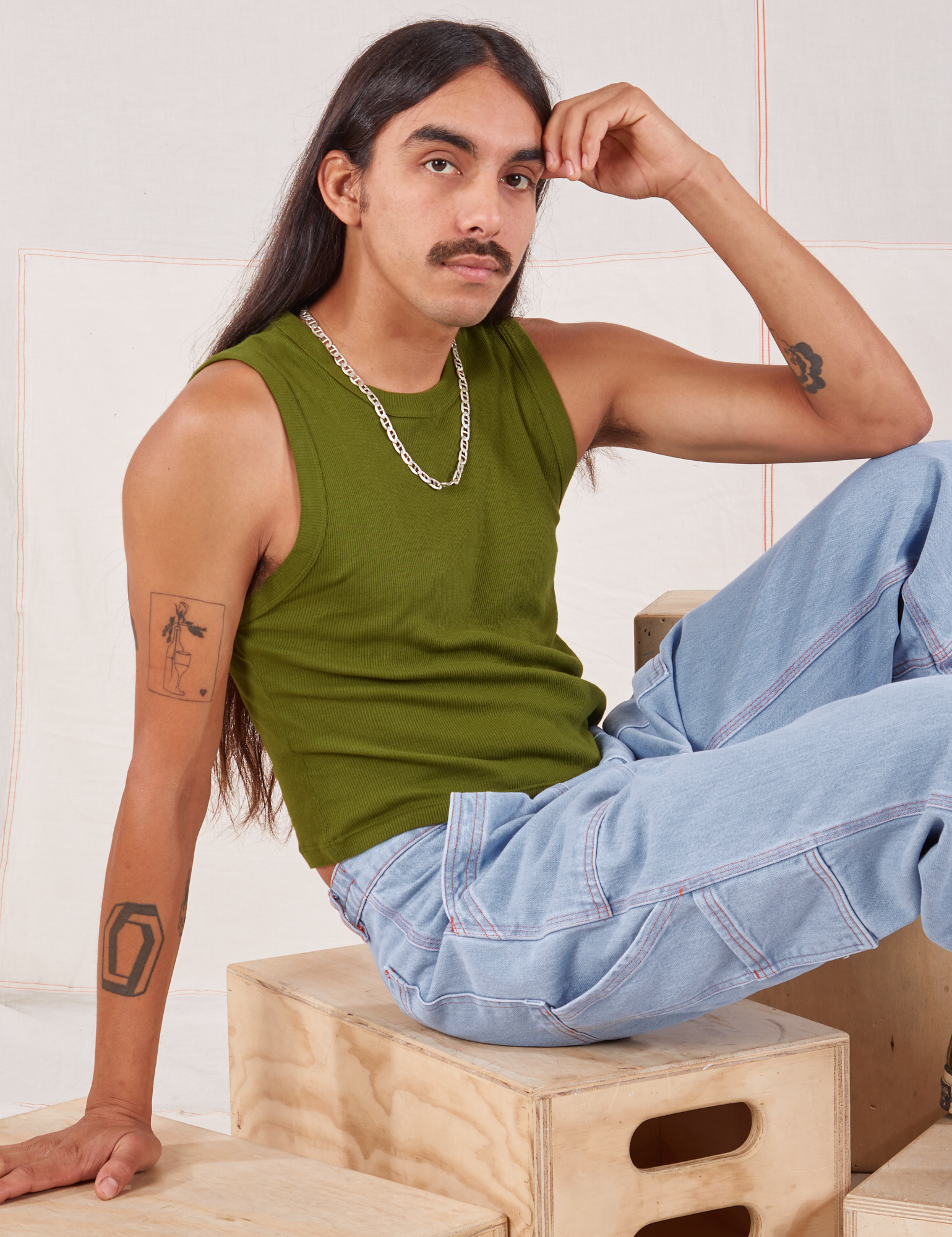 Anthony is wearing Muscle Tee in Summer Olive and light wash Carpenter Jeans