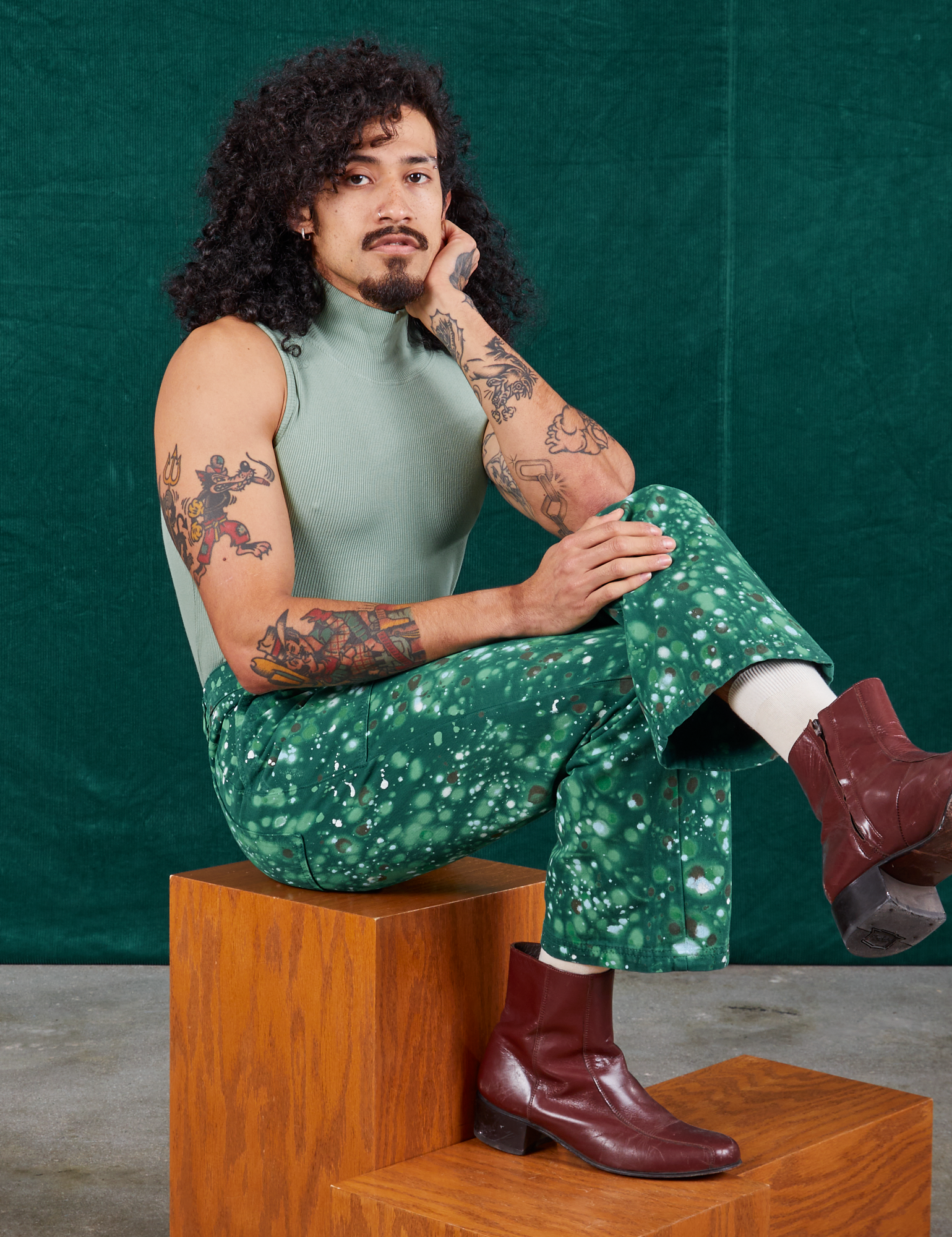 Jesse is wearing Marble Splatter Work Pants in Hunter Green and sage green Sleeveless Turtleneck