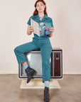 Alex is sitting on a vintage tv wearing Short Sleeve Jumpsuit in Marine Blue