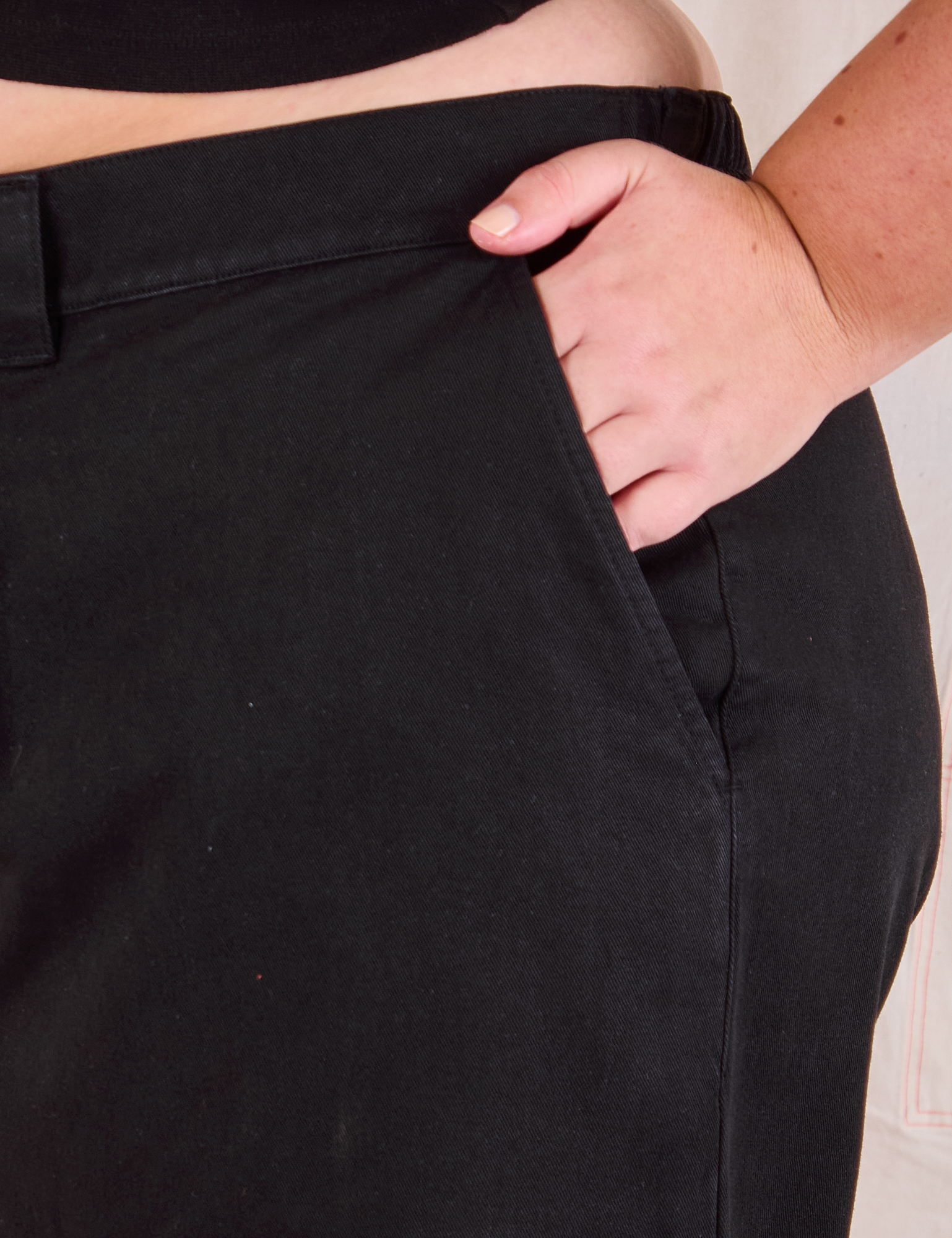 Mid-Rise Pleated Trousers in Basic Black close up of Juliet&#39;s hand in pocket.