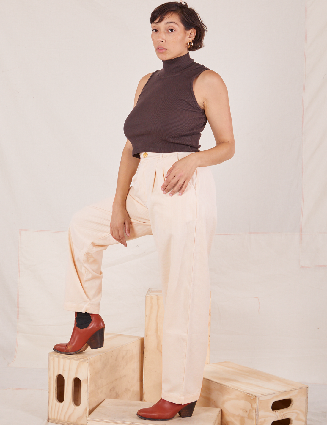 Tiara is wearing Heritage Trousers in Vintage Off-White and the Sleeveless Turtleneck in espresso brown