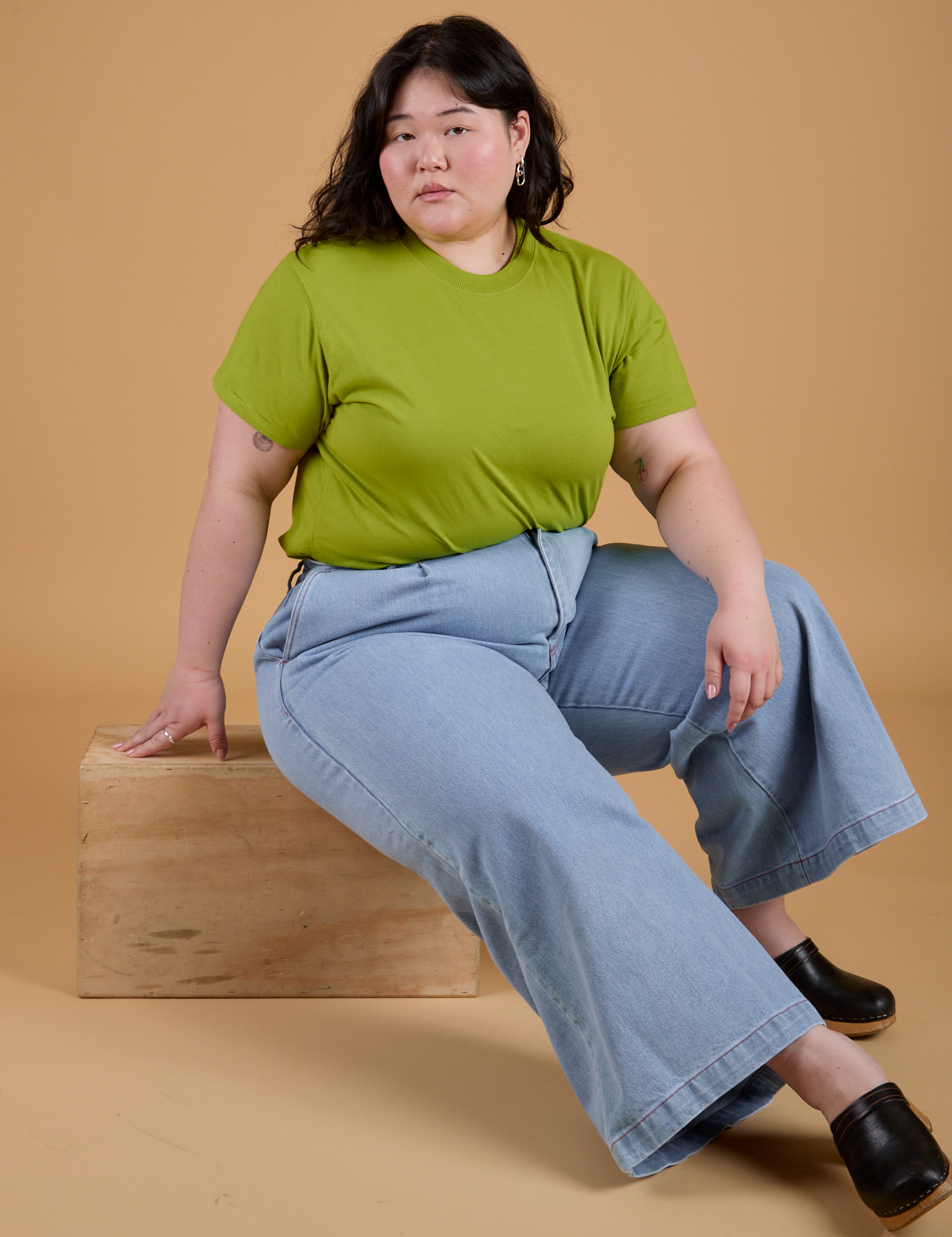 Ashley is wearing Organic Vintage Tee in Gross Green and light wash Indigo Wide Leg Trousers