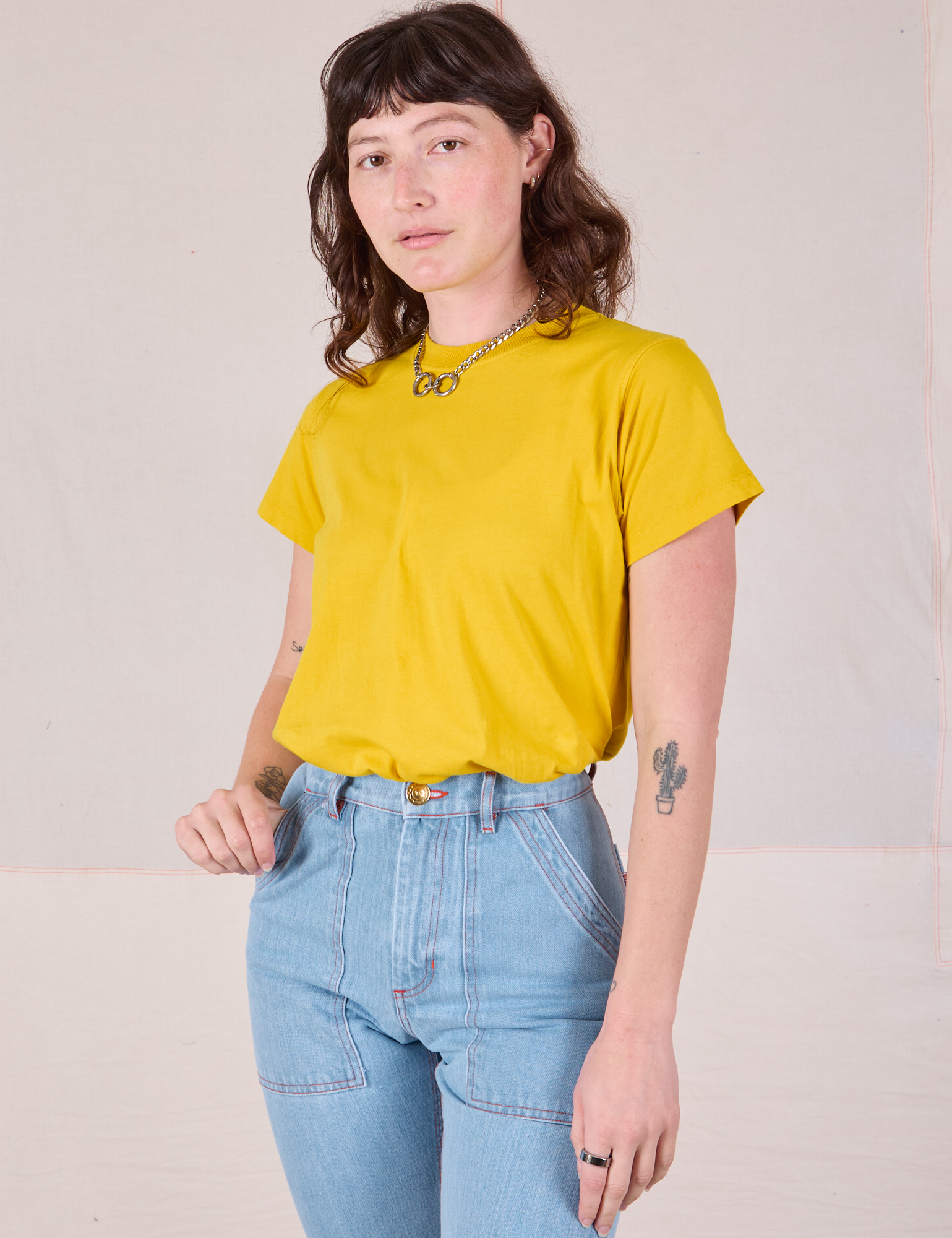 Alex is wearing Organic Vintage Tee in Golden Yellow tucked into light wash Carpenter Jeans