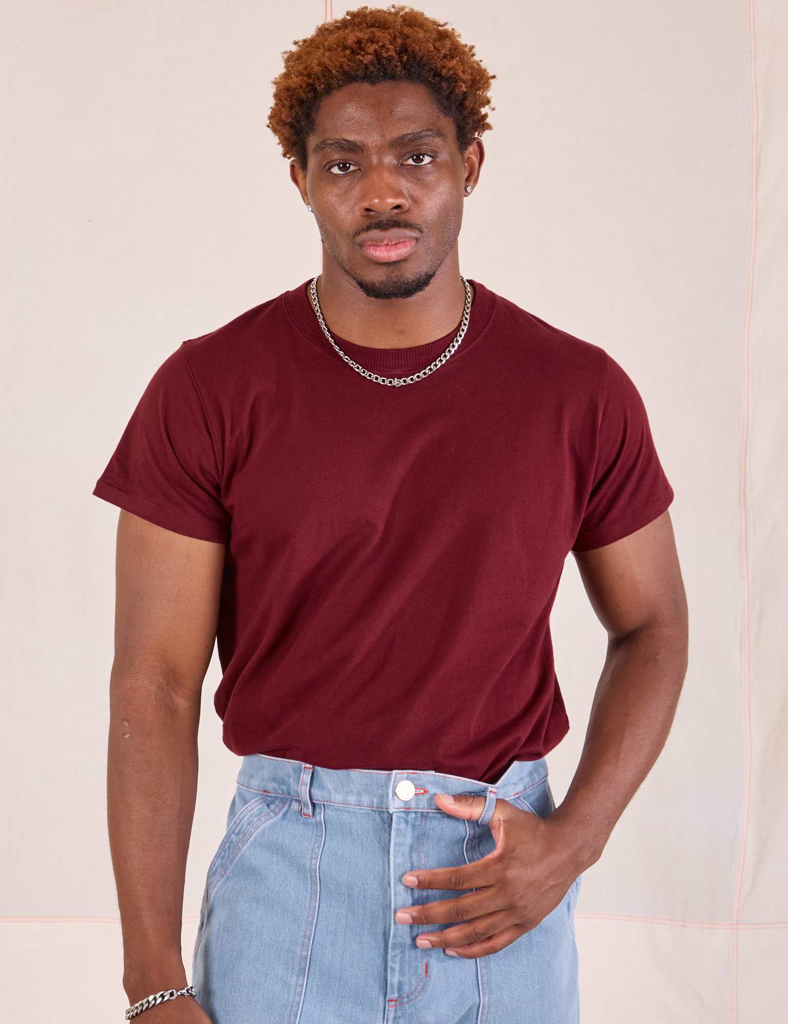 Issac is wearing Organic Vintage Tee in Red Wine tucked into light wash Carpenter Jeans