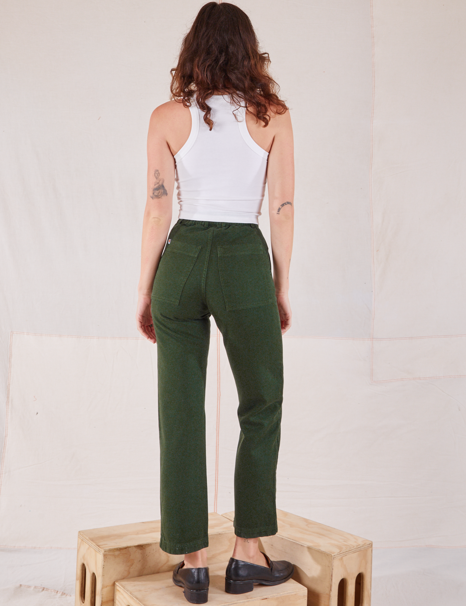 Back view of Organic Work Pants in Swamp Green and Racerback Tank in vintage tee off-white on Alex