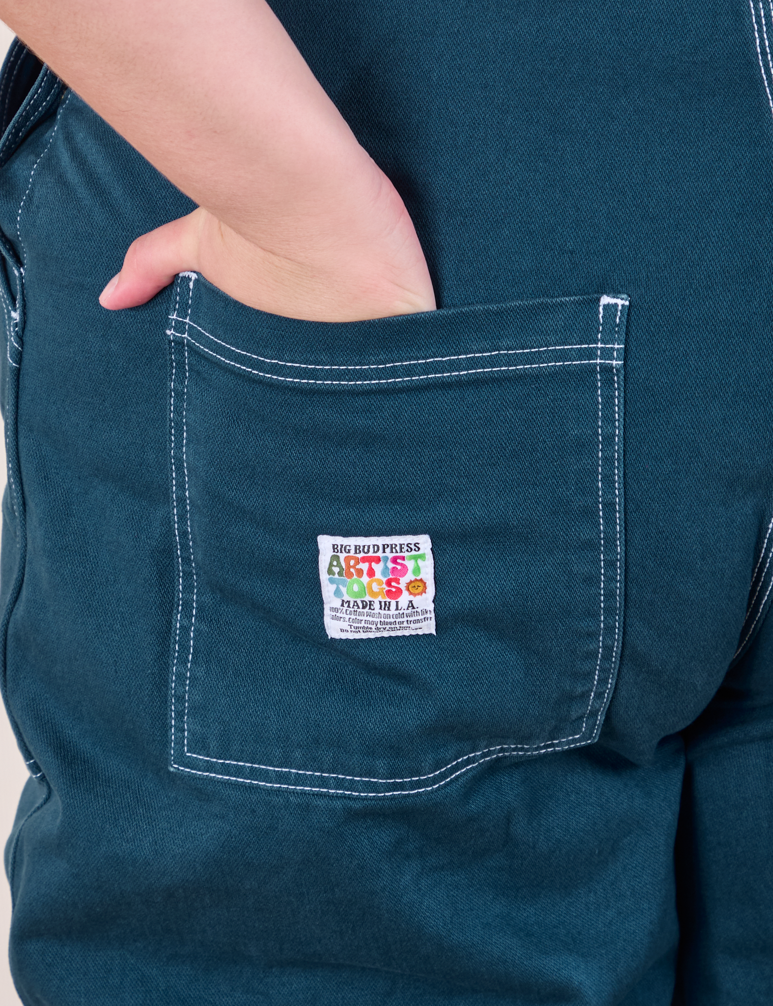 Original Overalls in Lagoon back pocket close up.  Marielena has her hand in the pocket.