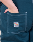 Original Overalls in Lagoon back pocket close up.  Marielena has her hand in the pocket.