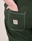 Original Overalls in Swamp Green back pocket close up. Marielena has her hand in the pocket.