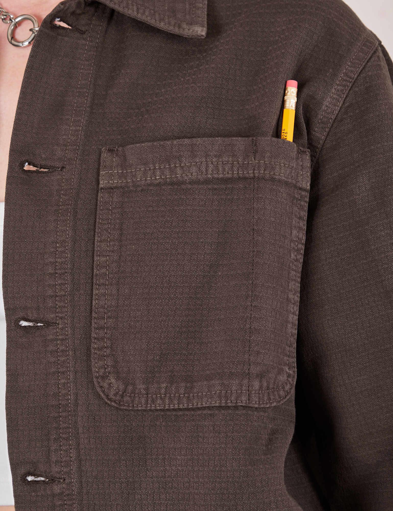 Field Coat in Espresso Brown front pocket close up. Pencil is in the pen pocket slot.