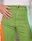 Front close up of Hand-Painted Stripe Western Pants in Bright Olive. Jesse has their thumb in the belt loop.