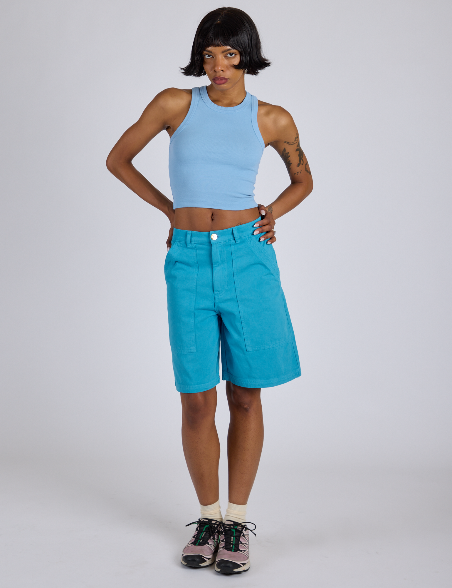 Kira is wearing Longline Work Shorts in Hawaiian Blue and baby blue Racerback Tank